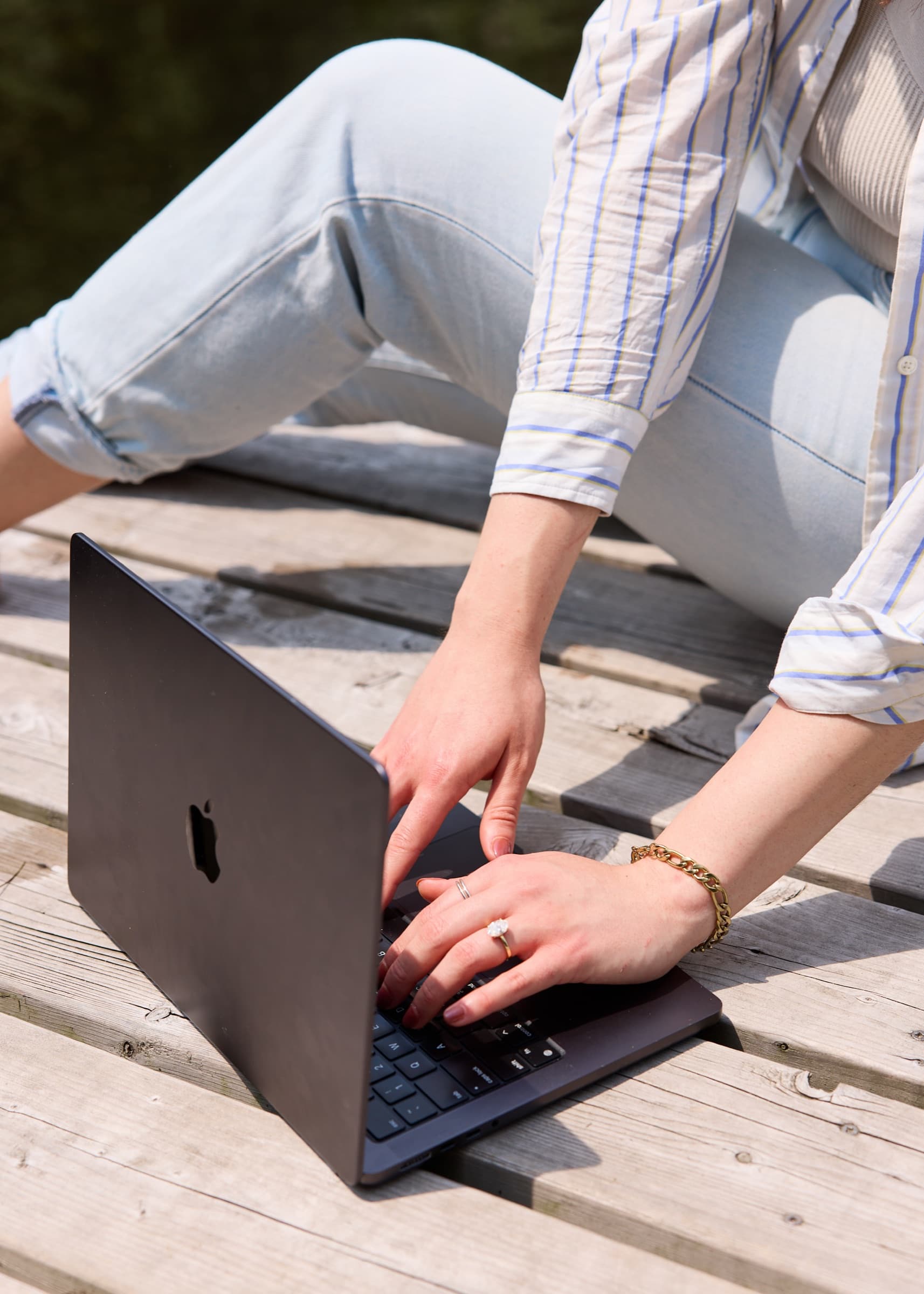 Hands typing on a laptop on a wooden dock, representing a wellness founder whose brand has not caught up to the business
