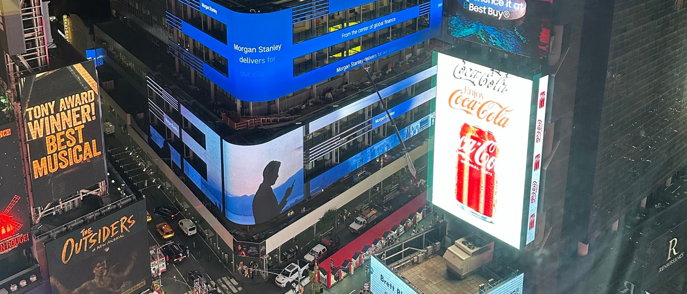 Night view across Times Square, cropped to show competing billboards and illuminated brand signage more clearly.