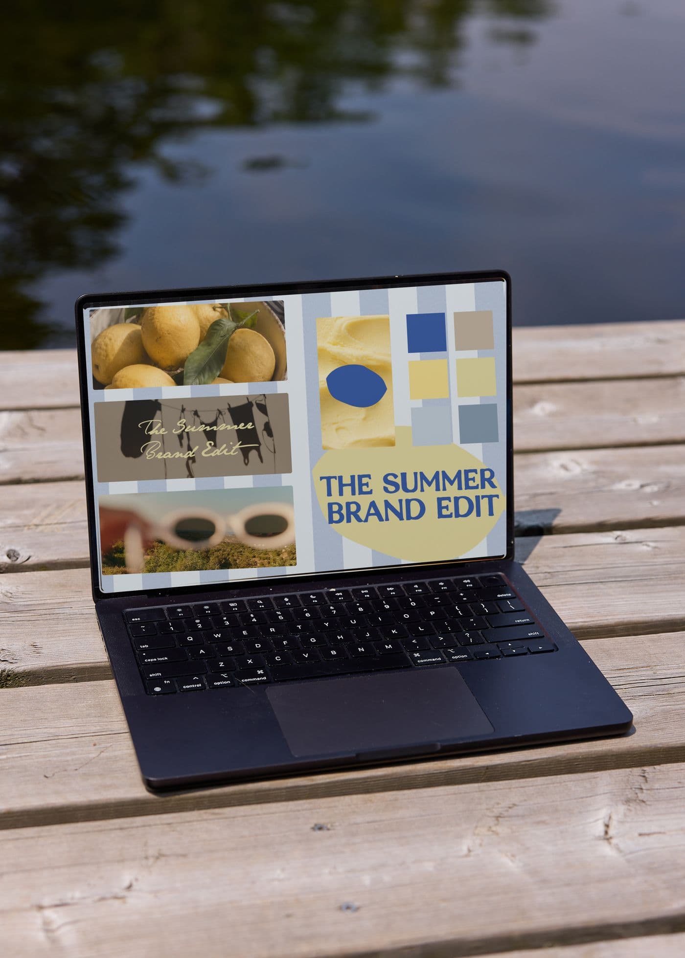 Laptop on a wooden dock showing The Summer Brand Edit moodboard with lemons, stripes, and colour swatches