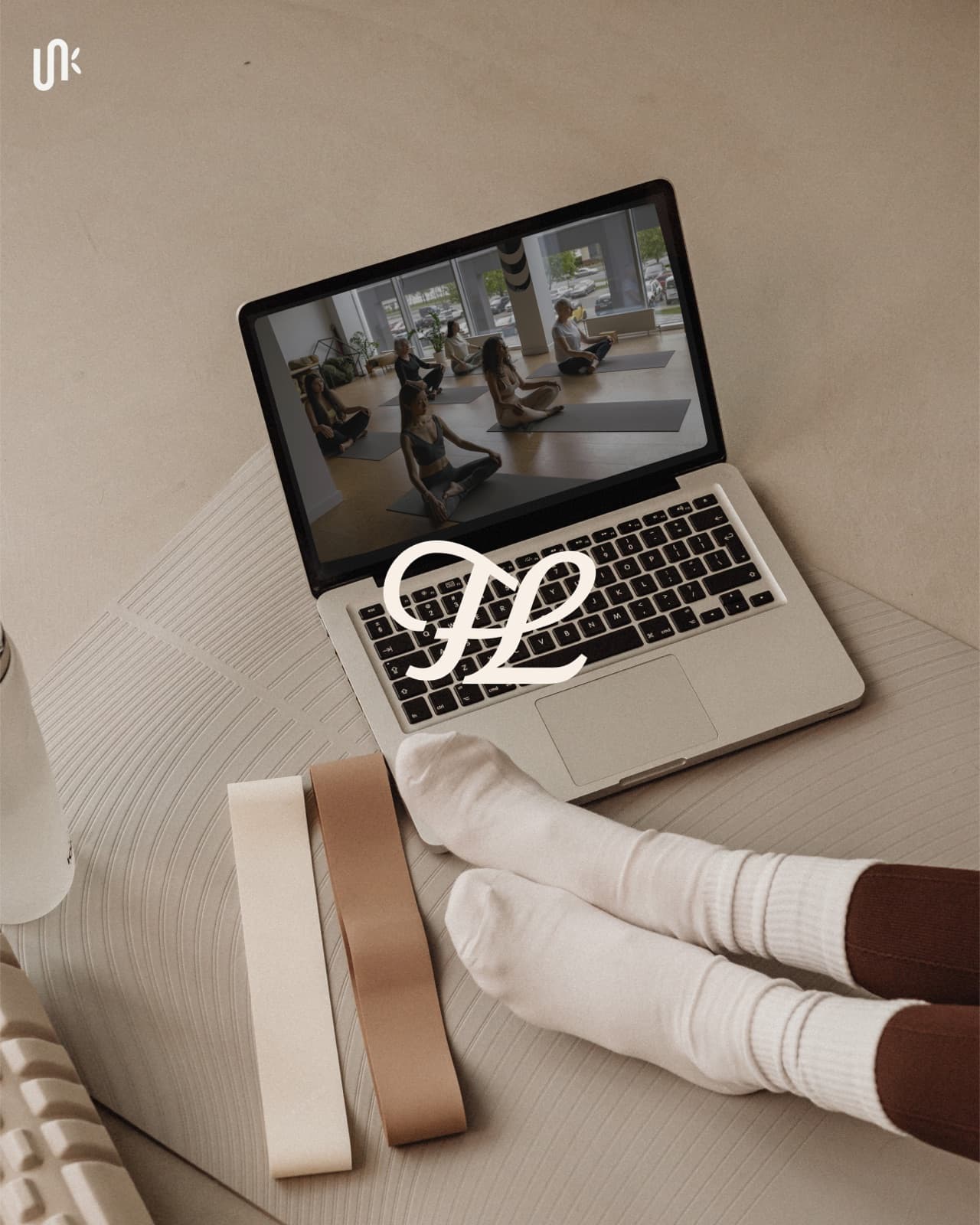 Cursive FL monogram over a laptop yoga class and home movement setup