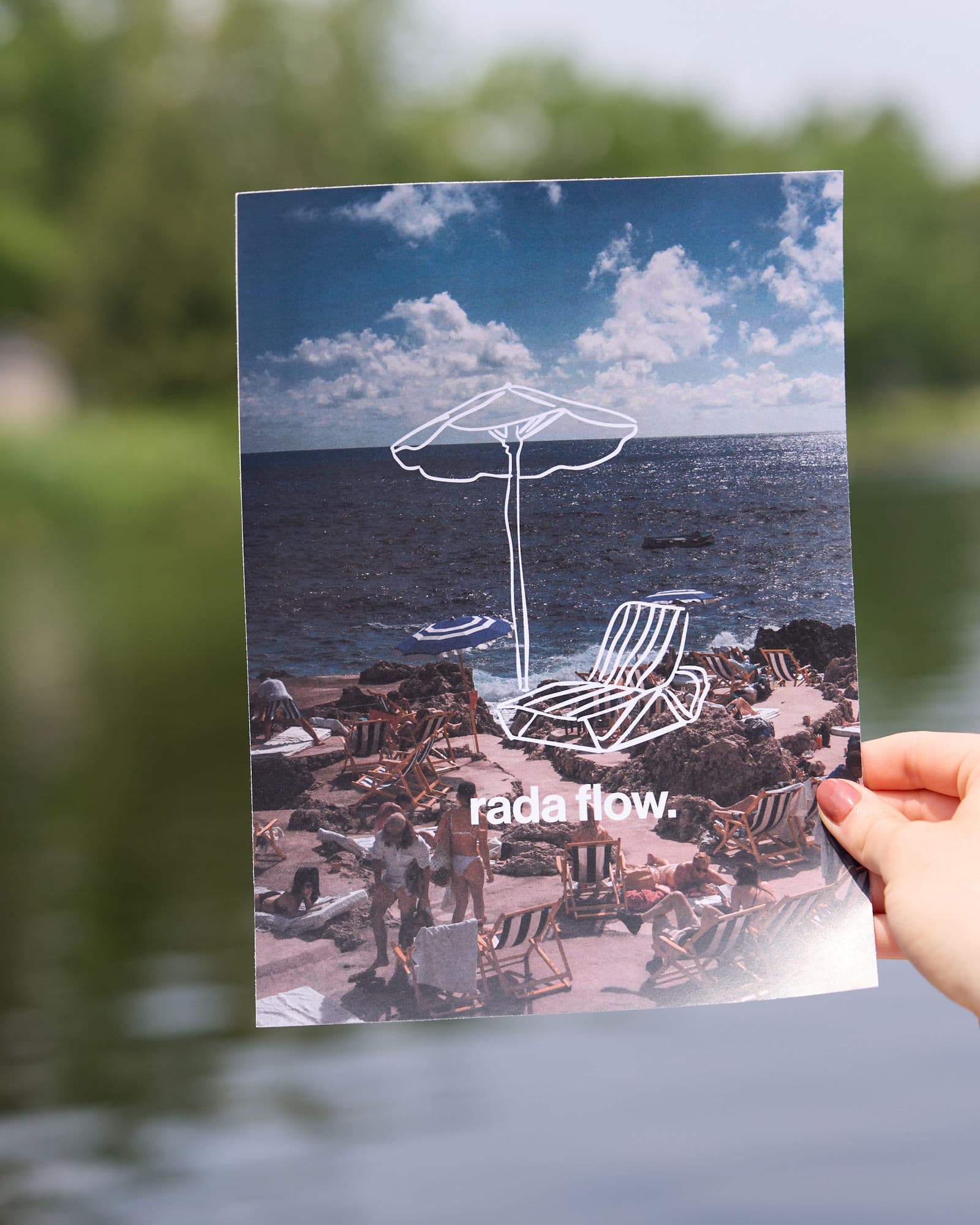 Hand holding a Rada Flow postcard with beach photography and lowercase wordmark