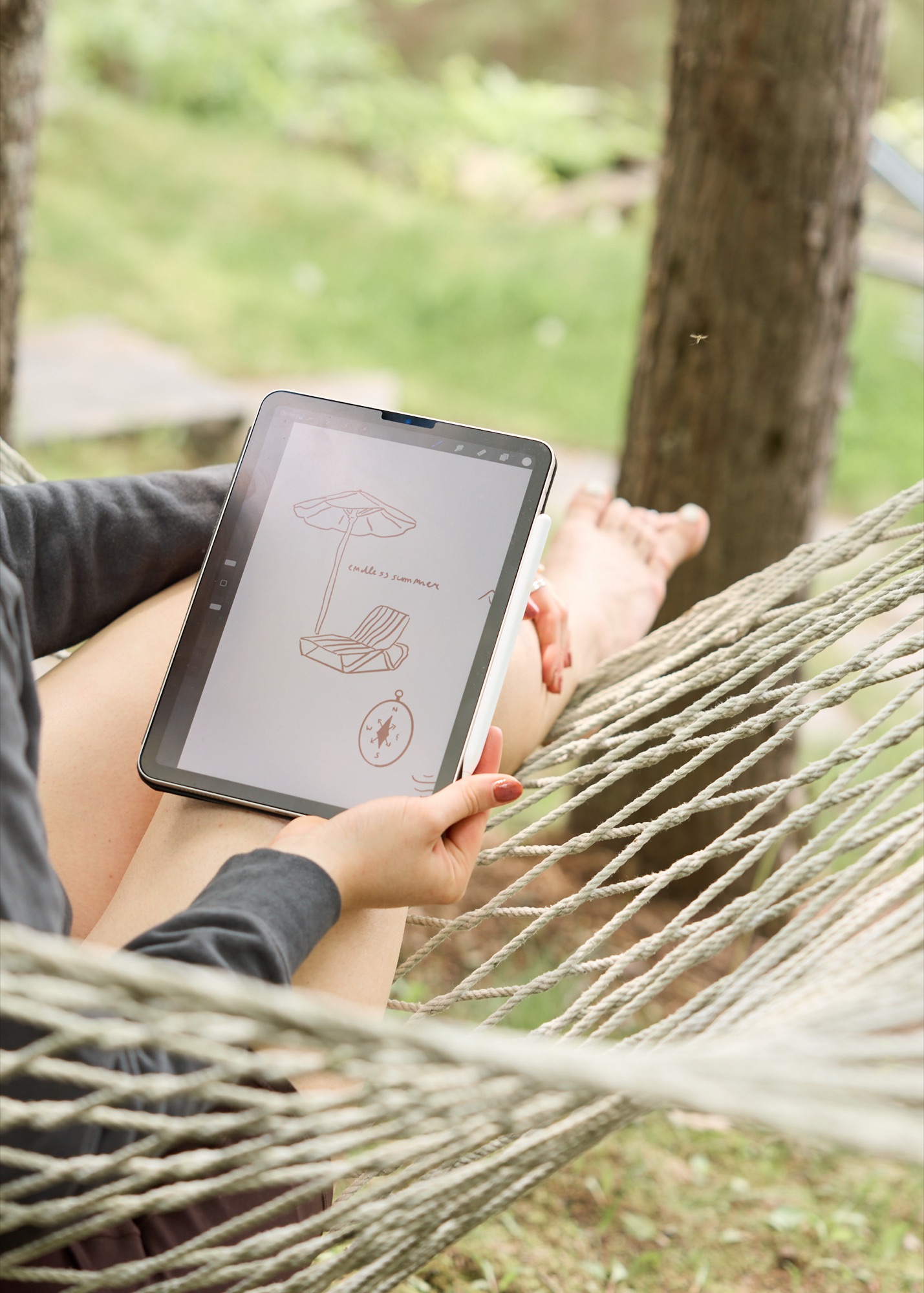 Hands sketching creative direction on a tablet while resting outdoors