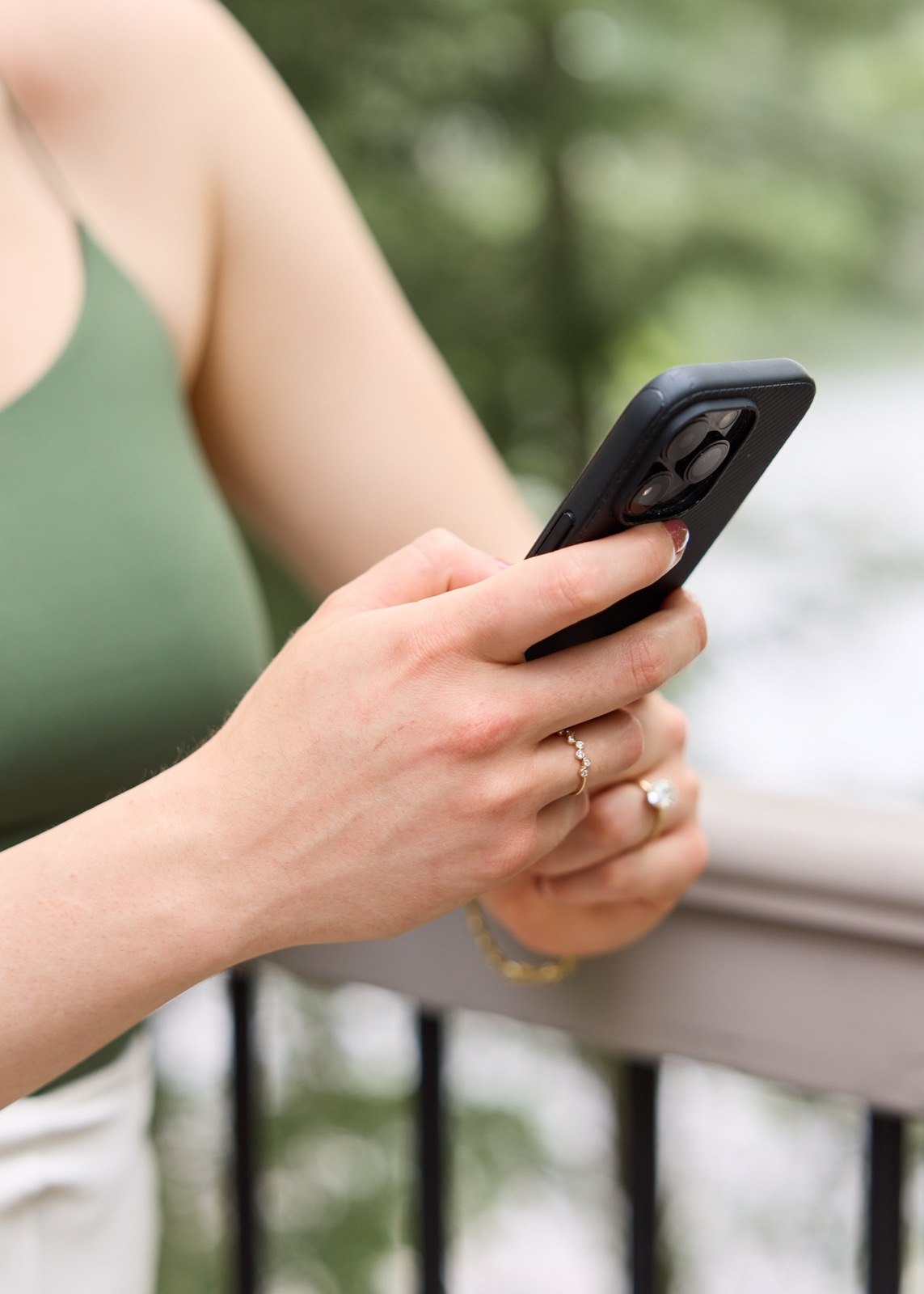 Hands holding a phone outdoors.