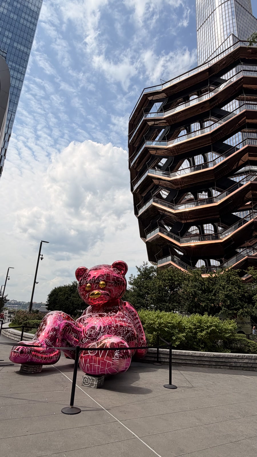 A bright pink graffiti-covered bear sculpture at Hudson Yards, standing out against The Vessel and surrounding towers.