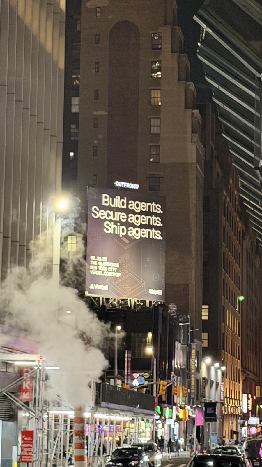 A Vercel billboard on a Midtown street at night, with clear campaign typography rising through steam and city light.